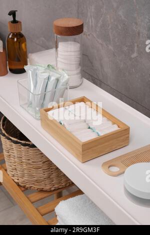 De nombreux tampons et produits de soins personnels différents sur table blanche près du mur gris Banque D'Images