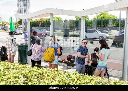 Miami Beach Florida, couvert arrêt d'autobus public passagers attendant hommes femmes couples, Miami-Dade Metrobus Banque D'Images