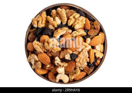 Noix mélangées brutes isolées sur fond blanc. Noix, amandes, noisettes et raisins secs dans un bol à noix de coco. Vue de dessus Banque D'Images