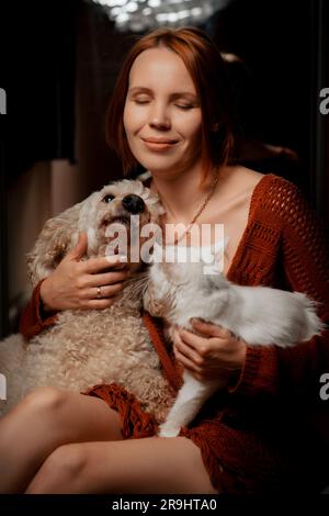 Belle femme de quarante ans avec un chat blanc et un chien.Concept de soins pour animaux. Banque D'Images