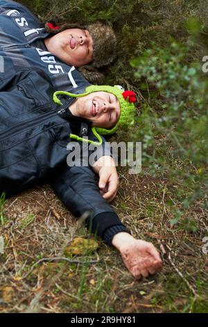 Ivre, gueule de bois et des garçons avec des amis dormant à l'extérieur sur un terrain ensemble le matin après une fête. Herbe, fatigué ou alcoolisme avec une taille plus Banque D'Images