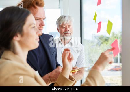 Homme d'affaires senior par des collègues discutant des post-it Banque D'Images