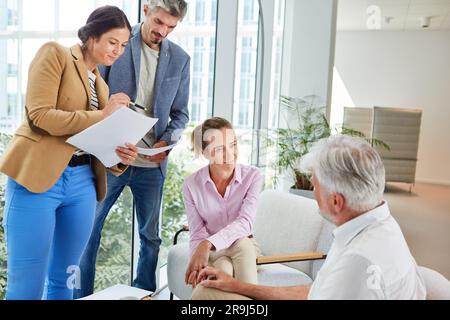 Homme d'affaires senior discutant avec des collègues masculins et féminins Banque D'Images