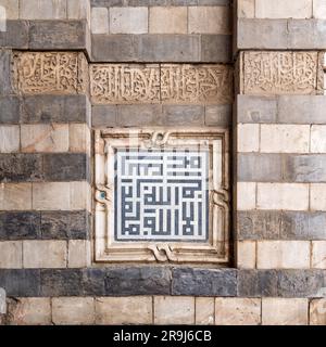 Unité de décoration en marbre avec calligraphie islamique sur le mur de pierre extérieur de la mosquée Sultan al Muayyad, le vieux Caire, Egypte. Le texte traduit: Au nom d'Allah, le bénéfique, le miséricordieux Banque D'Images