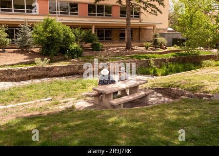 Un homme et une femme âgés s'assoient à une table de pique-nique dans une zone herbeuse au bord de la rivière Santa Fe, dans le centre-ville de Santa Fe, au Nouveau-Mexique, aux États-Unis. Banque D'Images