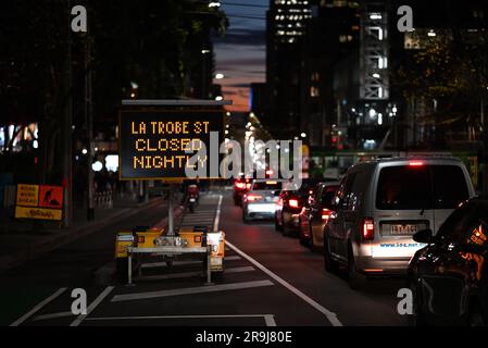 La circulation en direction de l'ouest s'est arrêtée sur la rue la Trobe à côté d'un panneau d'avertissement de fermetures de route nocturnes, tôt en soirée d'hiver Banque D'Images