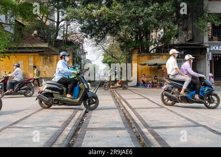 Hanoï, Vietnam-avril 2023 ; vue à angle bas d'une route animée avec des scooters traversant les voies de chemin de fer de la célèbre ligne de chemin de fer à travers le centre de la ville c Banque D'Images