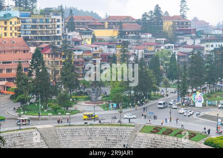 Sapa, Vietnam-avril 2023; vue en grand angle de la place principale de la ville occupée par la circulation, les locaux et les touristes avec le nom de la ville dans lit de fleur Banque D'Images