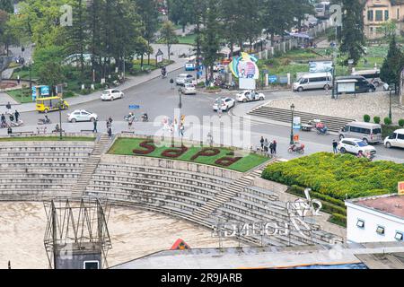 Sapa, Vietnam-avril 2023; vue en grand angle de la place principale de la ville occupée par la circulation, les locaux et les touristes avec le nom de la ville dans lit de fleur Banque D'Images