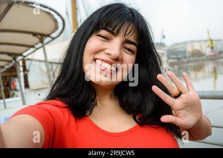 Portrait selfie de la jeune femme latine d'origine vénézuélienne vêtue de rouge, avec des cheveux noirs, souriant plein air, touriste dans la ville de Buenos Aires Banque D'Images