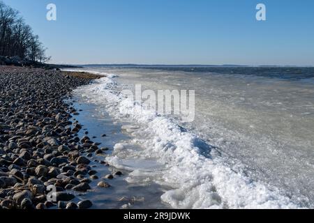 Vue à angle bas sur les vagues de glace, de slurpee ou de neige fondante sur la plage de galets Greenwich point, Greenwich, CT, États-Unis avec glace formant au bord de la plage et long Island in Banque D'Images