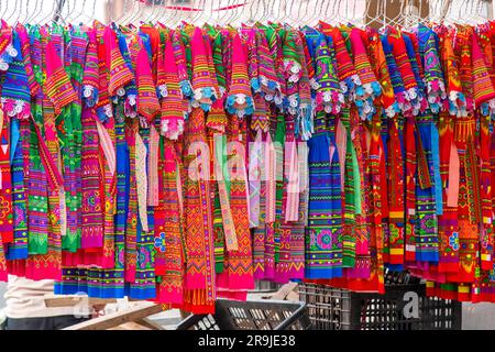 Vue sur un grand nombre de robes traditionnelles colorées de Fleur Hmong et Giay personnes accrochées sur une ligne à vendre sur le bac Ha, marché du dimanche du Vietnam Banque D'Images