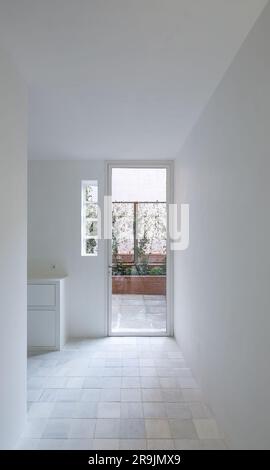 Design intérieur de la chambre minimaliste peinte entièrement blanc armoire en bois et porte avec des lunettes latérales dans le mur entrant dans le balcon décoré avec des plantes Banque D'Images