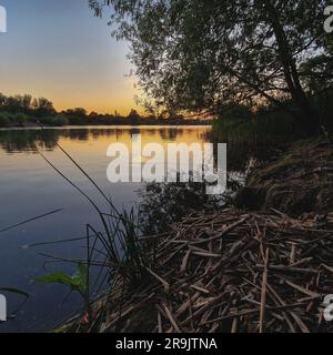 La photo capture un coucher de soleil hypnotisant sur le lac Croxall au Royaume-Uni. Le ciel est éclatant avec des teintes vibrantes d'orange, de rose et de pourpre, moulé Banque D'Images