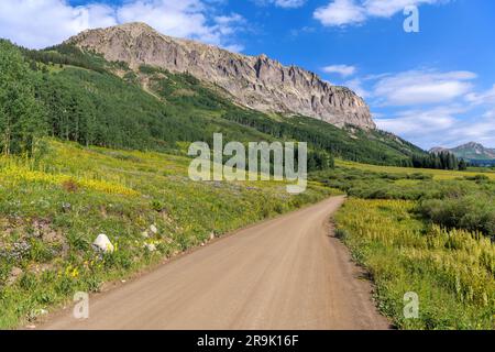 Gothic Road - Une belle vue d'été matinale sur une route de campagne pittoresque non pavée, Gothic Road, qui s'enroule au pied de la montagne gothique accidentée. Crested Butte, CO Banque D'Images