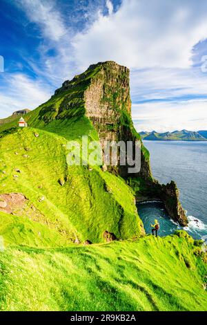 Randonneur admirant le phare de Kallur et le sommet de la montagne de Borgarin au sommet des falaises, île de Kalsoy, îles Féroé, Danemark Banque D'Images