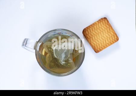 verre transparent de thé tisane dans un sac sur un fond blanc vue du dessus et des biscuits Banque D'Images