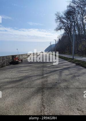 Un quai avec plusieurs personnes au loin. Boulevard en bord de mer à Gdynia, Pologne. Banque D'Images