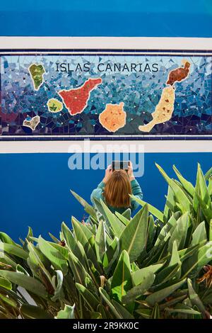 Ténérife, Espagne - 27 juin 2023: Femme méconnaissable prenant une photo avec son téléphone portable d'une carte des îles Canaries. Banque D'Images