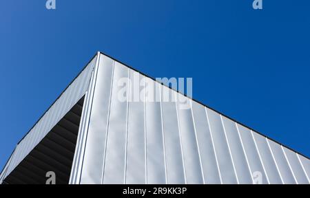 Architecture industrielle abstraite avec un coin de métal gris brillant intégré sous le ciel bleu par une journée ensoleillée Banque D'Images
