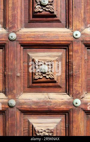 Sculpture d'une fleur dans le bois d'une vieille porte. Banque D'Images