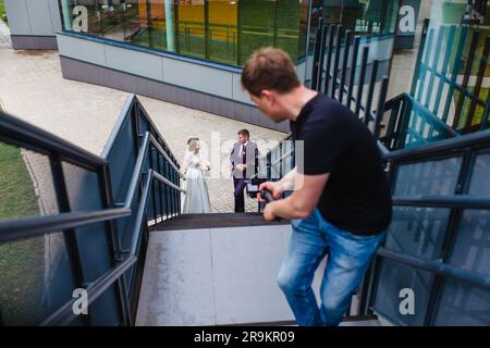 Un vidéaste professionnel de mariage photographie un film avec les jeunes mariés sur les escaliers Banque D'Images