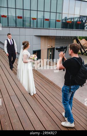 Un vidéaste professionnel de mariage photographie un film avec les jeunes mariés sur les escaliers Banque D'Images