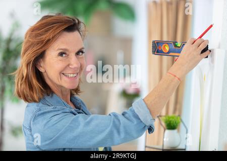 décorateur se préparant à accrocher l'image au mur Banque D'Images