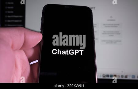 Utilisateur tenant smartphone avec ChatGPT mot logo, et dans le fond flou le site Web de ChatGPT invite de commande développé par OpenAI. Banque D'Images