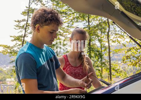 Deux grimpeurs déchargent leur équipement d'une voiture, se préparant à embarquer pour leur prochaine aventure d'escalade Banque D'Images