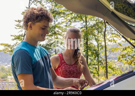 Deux grimpeurs déchargent leur équipement d'une voiture, se préparant à embarquer pour leur prochaine aventure d'escalade Banque D'Images