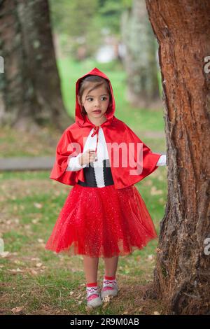 Jolie fille portant un petit costume de cagoule rouge. Une vraie famille s'amusant en utilisant les costumes du petit conte de cagoule rouge à Halloween. Banque D'Images
