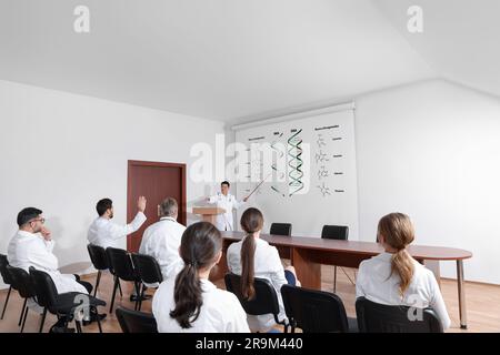 Conférence sur la différence entre l'ARN et l'ADN. Professeur utilisant l'écran de projection avec l'illustration pour le public dans la salle de conférence Banque D'Images