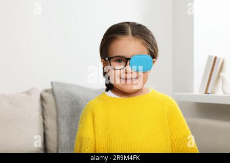 Bonne fille avec embout sur les verres pour le traitement du strabisme dans la chambre Banque D'Images