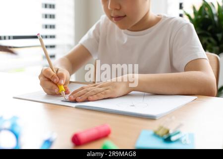 Un joli garçon fait un dessin avec une règle et un crayon. Leçons à la maison. Géométrie et dessin. Banque D'Images
