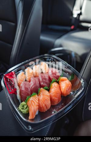 Une assiette de client remplie d'une sélection de sushis Costco occupe le devant de la scène sur la photo. Les sushi sont magnifiquement arrangés, mettant en valeur leur attrait artistique. La légende qui l'accompagne décrit la rentabilité du repas et la commodité de déguster des sushis pendant les achats chez Costco. Costco, le célèbre détaillant en gros, a pris une mesure audacieuse en ajoutant des sushis à son menu de restauration abordable. L'introduction de cette nouvelle cuisine s'est traduite par de longues files d'attente et des temps d'attente accrus, car les membres impatients se précipitent pour goûter la dernière offre de Costco.les clients n'ont pas perdu de TI Banque D'Images