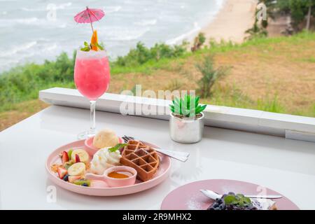 Queue de macktail rose sur comptoir blanc avec gaufres, glace et fruits frais. Banque D'Images