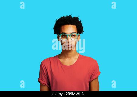 jeune homme adulte, pensant, regardant l'appareil photo portant des lunettes et des cheveux afro Banque D'Images