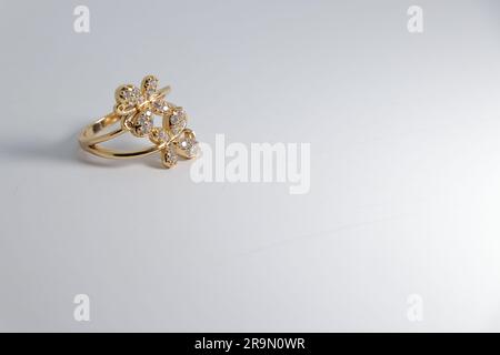 Brilliance élégante : bague d'or artificielle avec pierre blanche sur toile blanche - parfait pour la vente en ligne! Banque D'Images