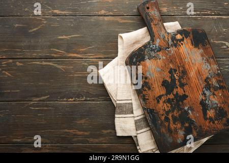 Planche à découper avec cuillères de cuisine et serviette rouge et persil, tomate pour cuisiner sur fond sombre en bois ancien. Cuisine végétarienne, santé ou cuisine con Banque D'Images