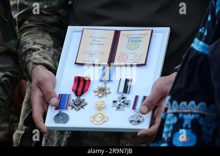 Kiev, Ukraine. 28th juin 2023. Un militaire tient des prix à côté du cercueil avec le corps du militaire Yury Samanyuk lors d'un adieu à la place de l'indépendance. Dans la guerre russo-ukrainienne, l'ancien commandant du groupe de pompiers mobiles séparé 'Oril' de la brigade mécanisée séparée 'Kholodny Yar' de la région d'Ivano-Frankivsk, Yuriy Samaniuk, est décédé en 93rd. Yuriy Samanyuk est originaire de Vorokhta, dans la région d'Ivano-Frankivsk. Dans la vie civile, il a été entraîneur dans les sports de main à main et a fait des meubles. Crédit : SOPA Images Limited/Alamy Live News Banque D'Images