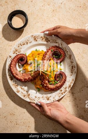 Un gros plan des mains tenant une plaque de topus tentacules, prêt à être apprécié Banque D'Images