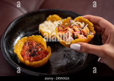 Une main tenant un tacos frais et sain avec des fruits de mer de l'assiette noire Banque D'Images