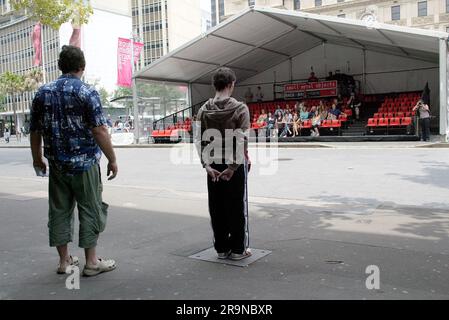 Les acteurs Allan V. Watt (à gauche) et Simon Laherty dans le théâtre de rue “Small Metal Objects”, où quatre acteurs sont micro tandis que le public écoute le dialogue avec un casque pendant qu’il se joue dans une rue urbaine animée. Festival de Sydney, Circular Quay, Sydney, Australie . 08.01.07. Banque D'Images