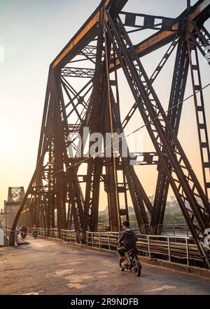 Le trafic de motos traverse la route partagée et le pont ferroviaire connu sous le nom de long Bien Bridge à la tombée de la nuit à Hanoi, Vietnam. Le pont date de 1903 et W Banque D'Images