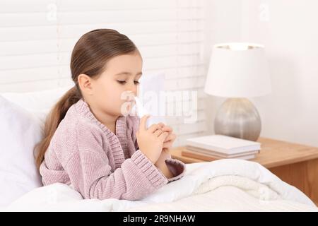 Petite fille utilisant un vaporisateur nasal dans la chambre Banque D'Images