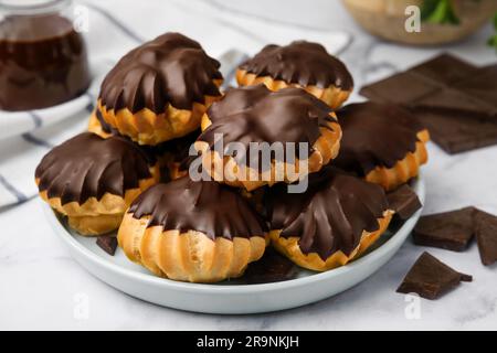 Délicieux profiteroles au chocolat sur table blanche, gros plan Banque D'Images