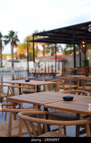 Tables et chaises en bois au bord de la piscine dans un hôtel Banque D'Images