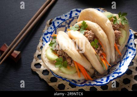 Concept alimentaire Buns Bao au bœuf bio ou Gua Bao dans une plaque en céramique asiatique sur fond noir avec espace copie Banque D'Images