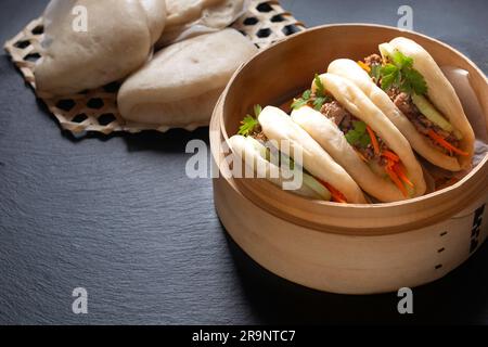 Concept alimentaire Buns Bao de bœuf bio ou Gua Bao dans plateau de ruisseau de bambou sur fond noir avec espace de copie Banque D'Images